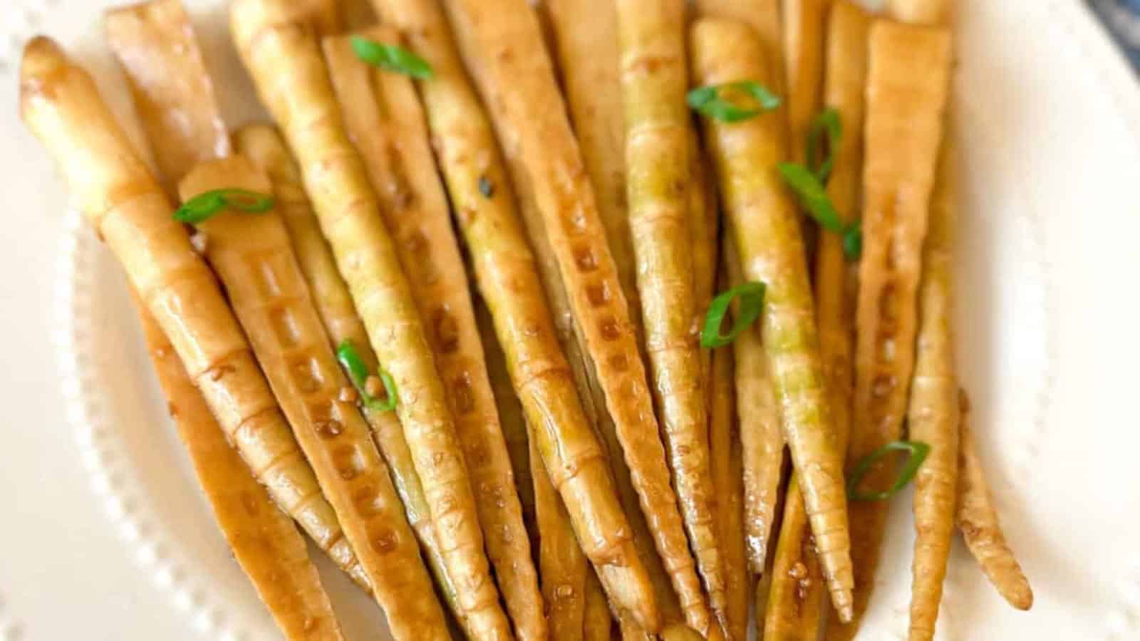 A plate of cooked braised bambo garnished with chopped green onions.