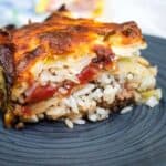 A slice of layered cabbage roll casserole served on a dark plate.