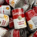 A pile of Campbell's Cream of Chicken soup cans, displaying labels with red and white design.