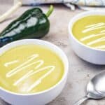 Two bowls of Cream of Poblano soup garnished with sour cream.