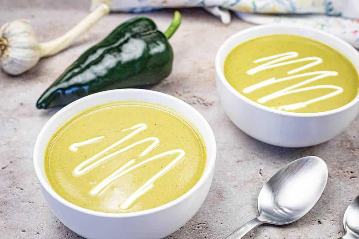 Two bowls of Cream of Poblano soup garnished with sour cream.