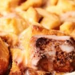 Close-up of glazed cinnamon pull-apart bread in a baking dish, featuring golden-brown pieces and sugar icing drizzle.