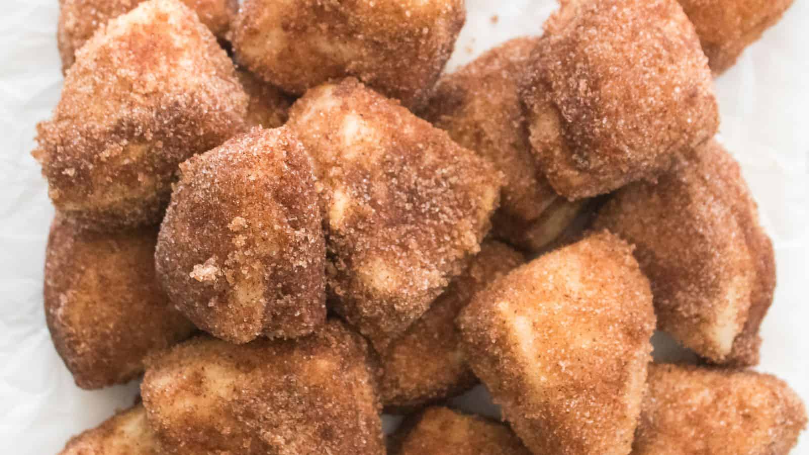 Close-up of Cinnamon Sugar Biscuit Bites, dusted in a sweet layer and piled on crisp white paper.