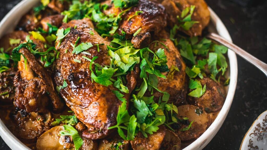 A plate of roasted chicken pieces garnished with fresh parsley leaves.