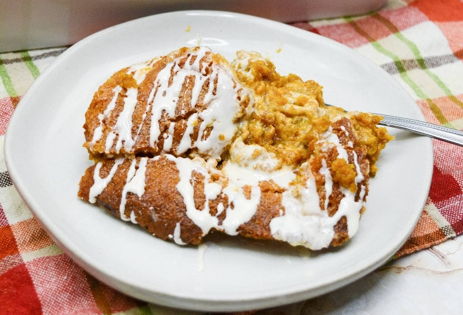 A plate with pumpkin cobbler, resting on a checkered tablecloth.