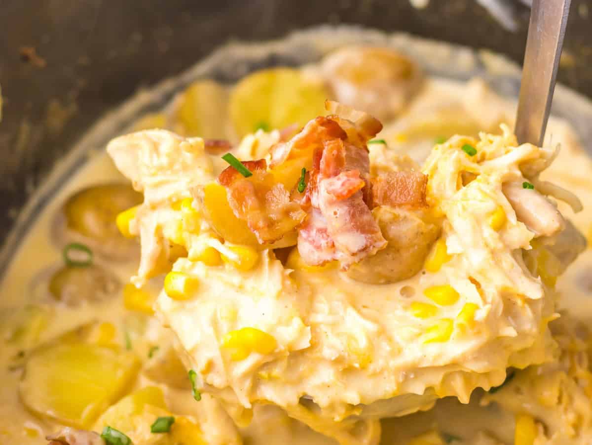 Close-up of a creamy chicken and corn chowder with chopped bacon and potatoes, garnished with fresh chives.