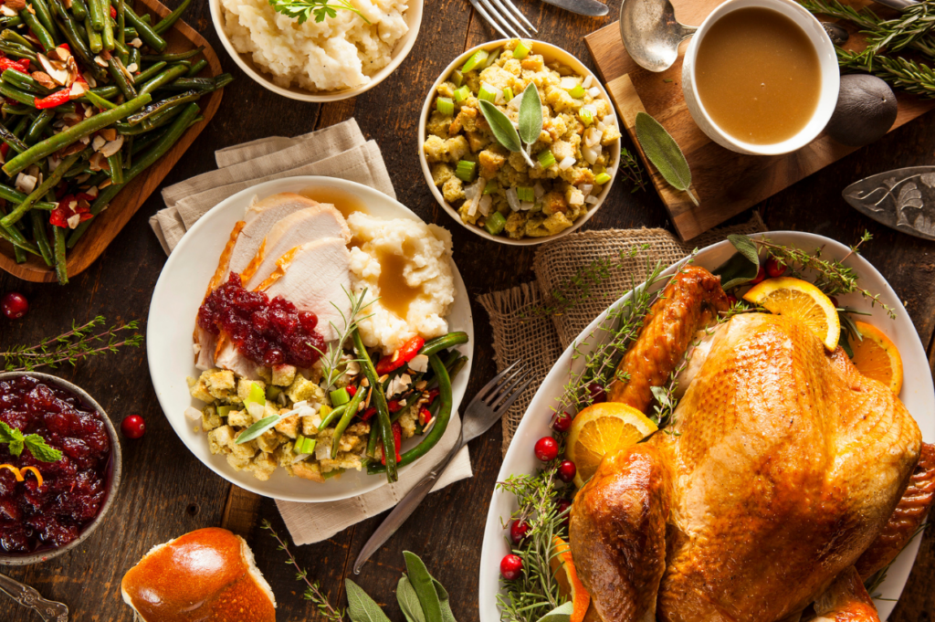 A Thanksgiving meal with roasted turkey, mashed potatoes, stuffing, green beans, cranberry sauce, and gravy is arranged on a wooden table—enjoy the holidays guilt-free.