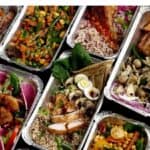 An assortment of colorful, plated Thanksgiving takeout meals in foil containers, featuring various meats, vegetables, grains, and garnishes.