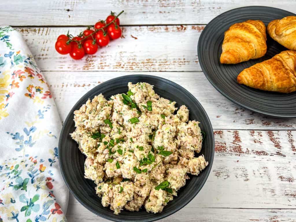 A bowl of Southern ham salad and croissants on a wooden table.