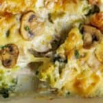 Close-up of a baked dish with melted cheese, mushrooms, and broccoli, showing a creamy texture and golden brown top.