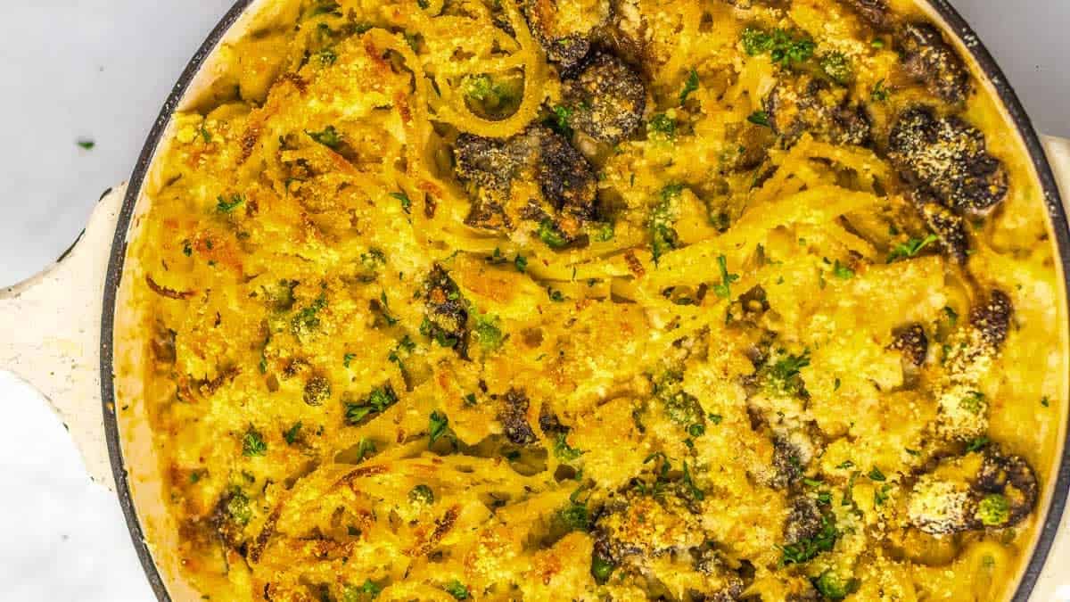 A dish of baked pasta with a golden crust, featuring visible mushrooms and parsley.