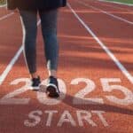 Person walking on a track with "2025 START" painted on it, symbolizing a new beginning or future goal.