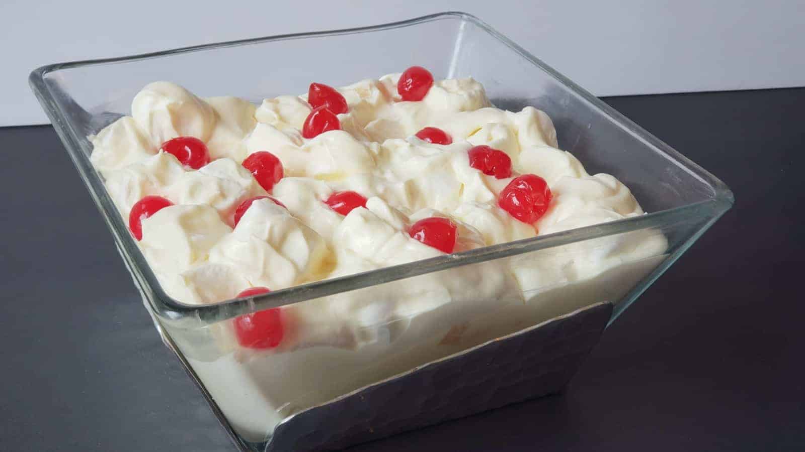 Bowl of marguerite salad topped with cherries on a black counter.