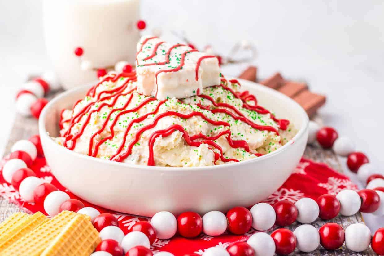 A festive tray of Christmas Tree Cake Crack, featuring broken pieces of white chocolate-coated crackers, topped with red drizzle and green sprinkles.