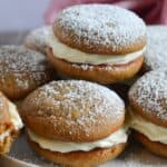 A plate of whoopie pies with cream filling, topped with powdered sugar.