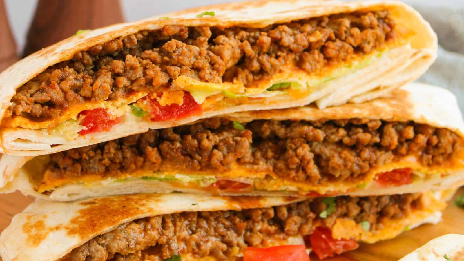 Close-up of stacked quesadillas filled with seasoned ground beef, melted cheese, and chopped tomatoes.