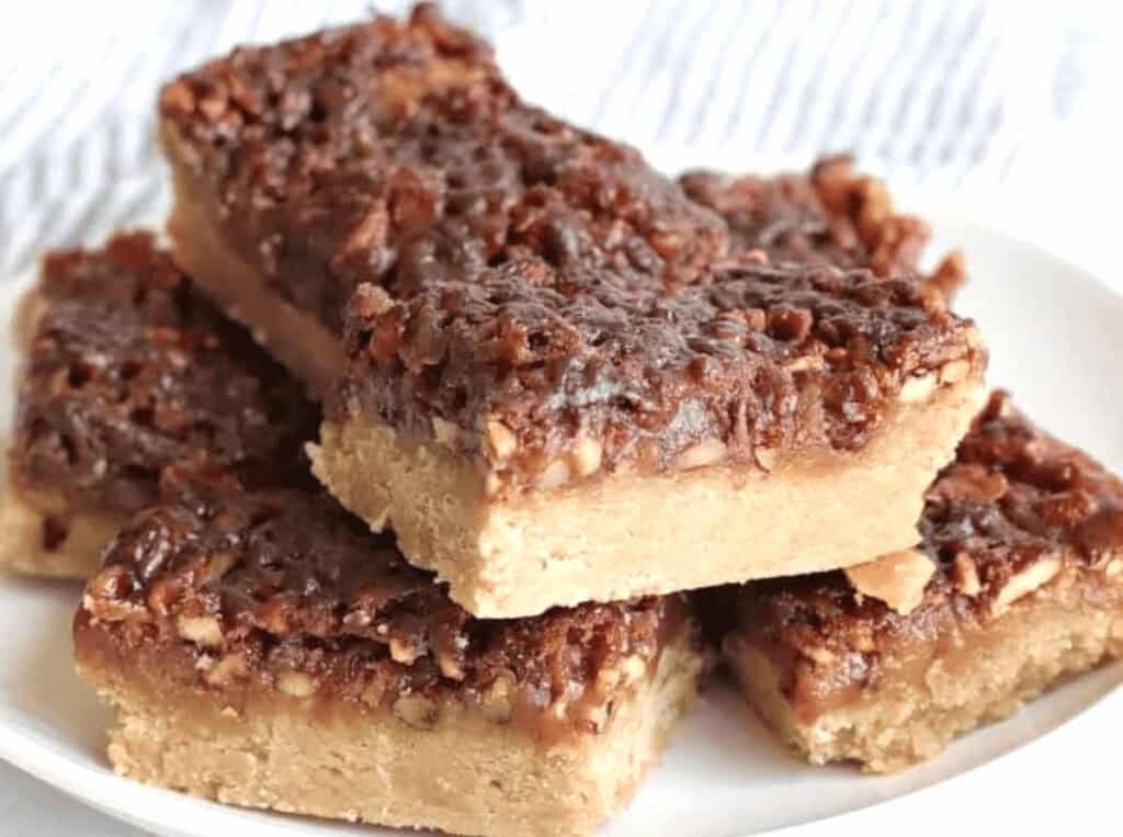 A plate of pecan pie bars with a crumbly base and a caramelized pecan topping.