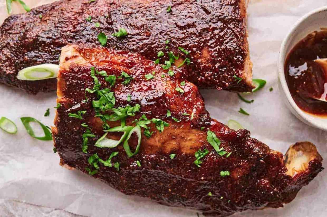 A stack of oven-baked ribs, garnished with fresh herbs.