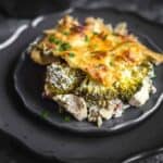 Cheesy broccoli and chicken casserole served on a dark scalloped plate.