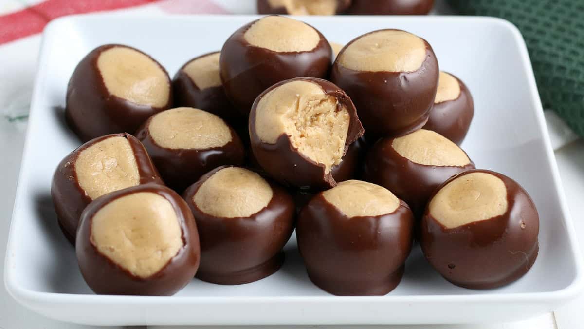 A white plate holding several chocolate and peanut butter buckeyes.