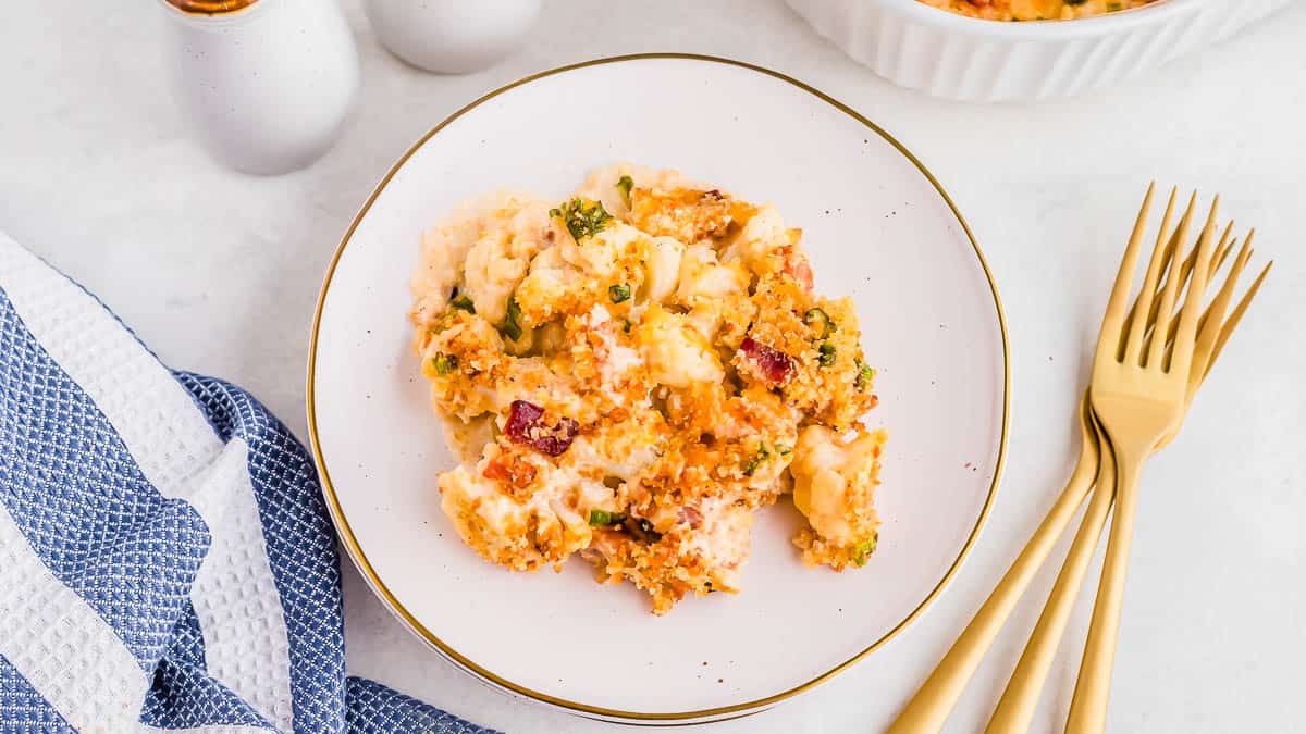 Cauliflower bacon gratin in a white baking dish with serving spoon.