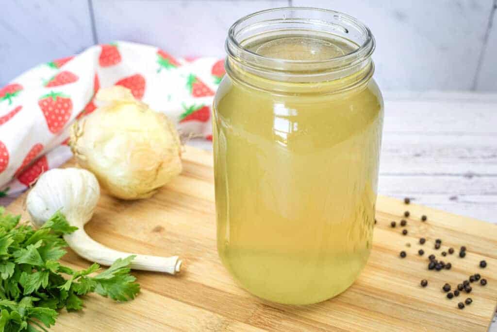 A jar of chicken broth on a wooden board.