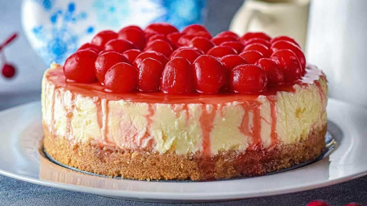 Cheesecake topped with glazed cherries on a white plate.