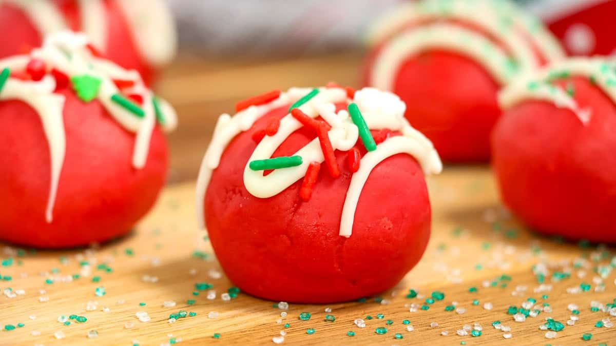 Close-up of red cake balls decorated with white icing and red and green sprinkles.