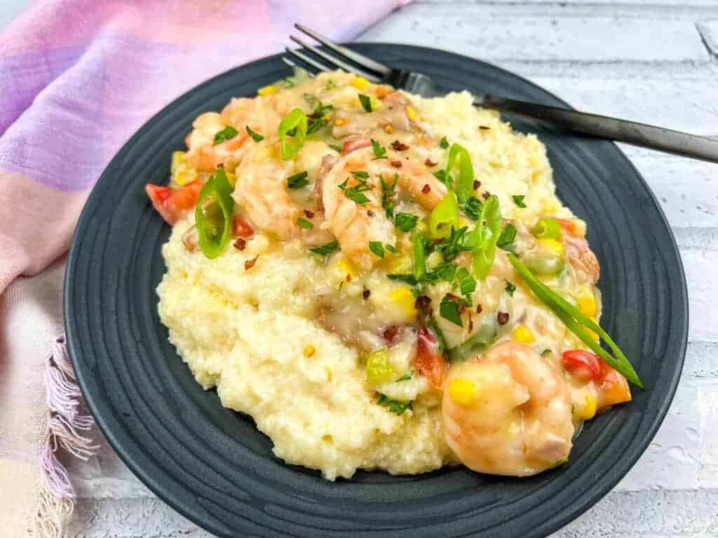 Close-up of shrimp and grits casserole with colorful veggies and spices.