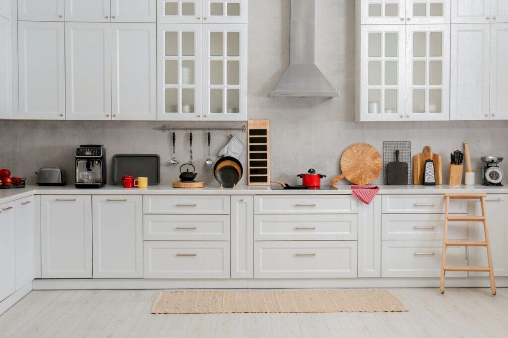 Modern kitchen refresh with white cabinets, countertop appliances, dishes, and cookware. A step ladder stands on the right.