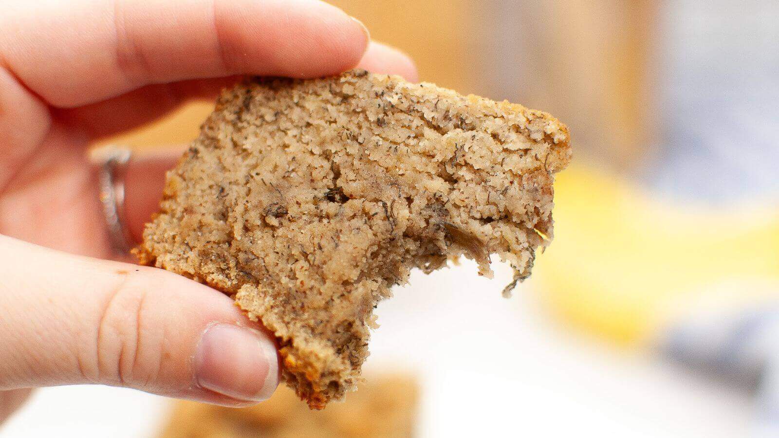 A hand holding a partially eaten slice of banana bread.