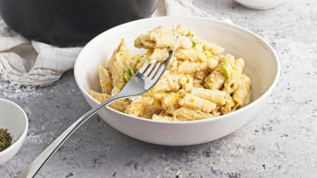 A bowl of creamy pasta with a fork resting inside.