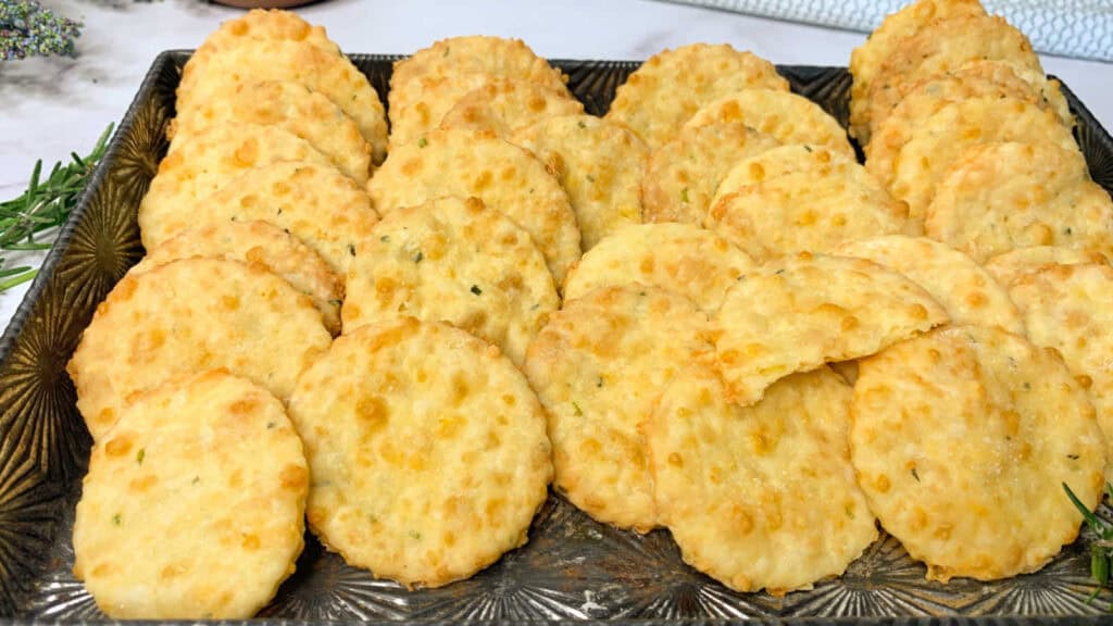 A tray filled with round, golden-brown cheese crackers arranged in neat rows.