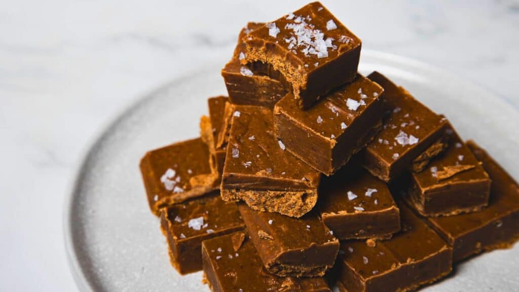 A plate of chocolate fudge squares stacked in a pyramid, topped with flaky sea salt.