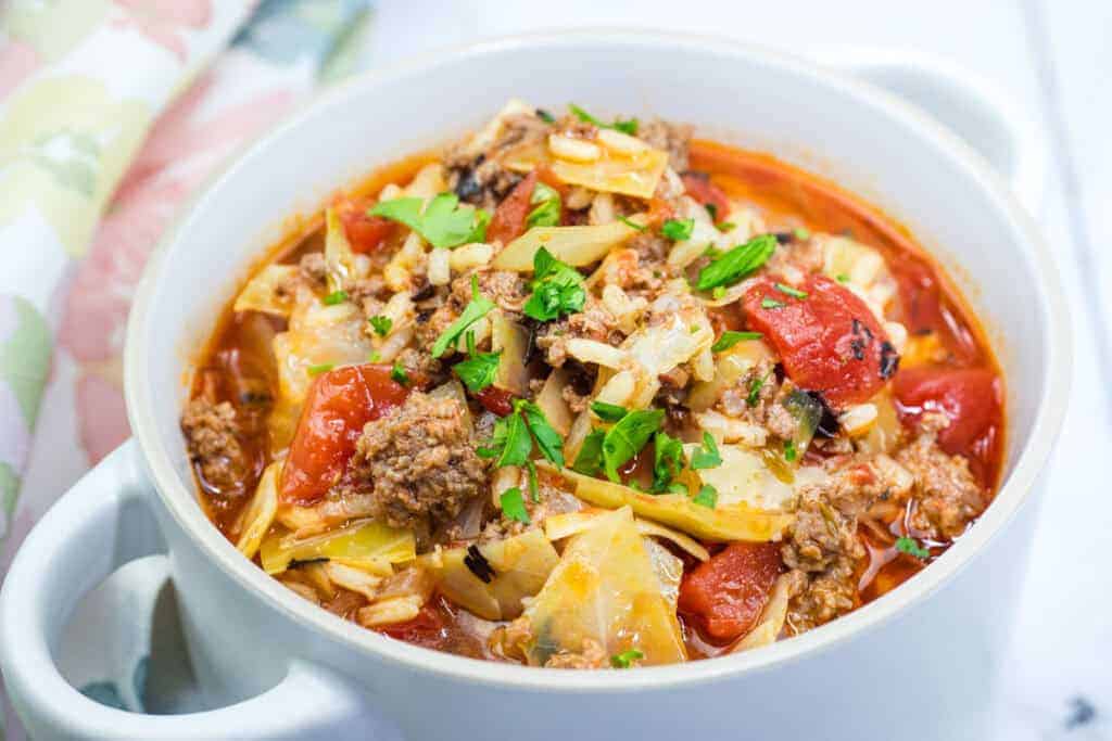 A bowl of cabbage roll soup garnished with chopped parsley.