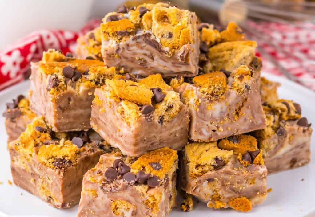 A stack of chocolate fudge squares with crushed cookies and chocolate chips, served on a white plate.