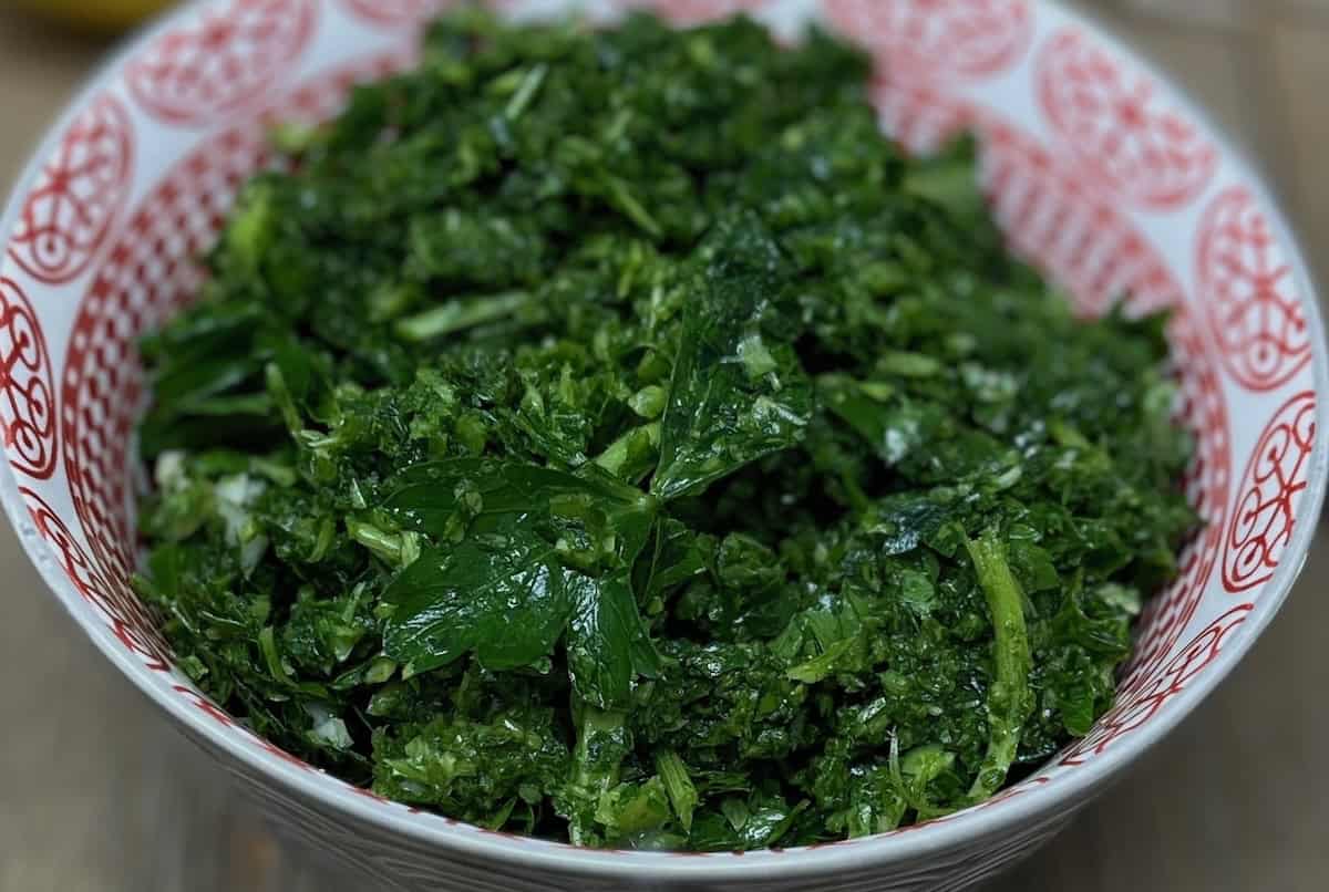 A bowl filled with chopped green leafy vegetables, placed on a table.