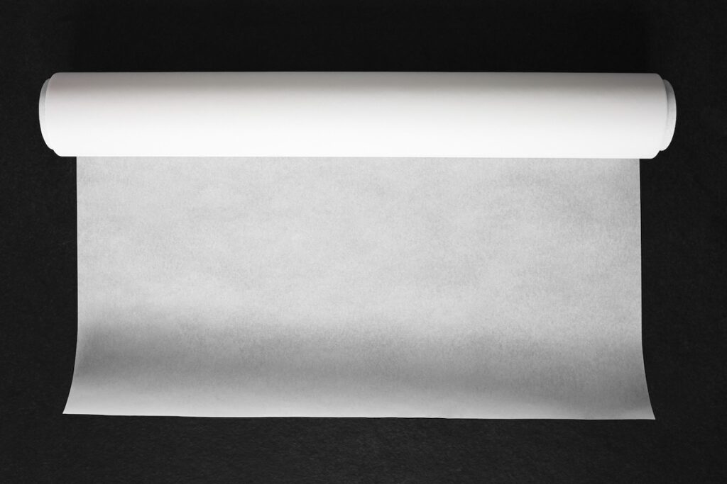 A roll of white parchment paper partially unrolled on a dark surface.