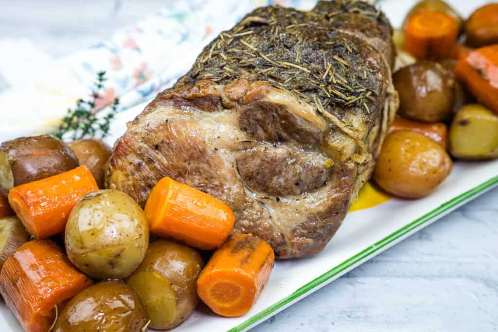 A plate with a Slow Cooker Herb-Crusted Pork Roast and roasted vegetables.