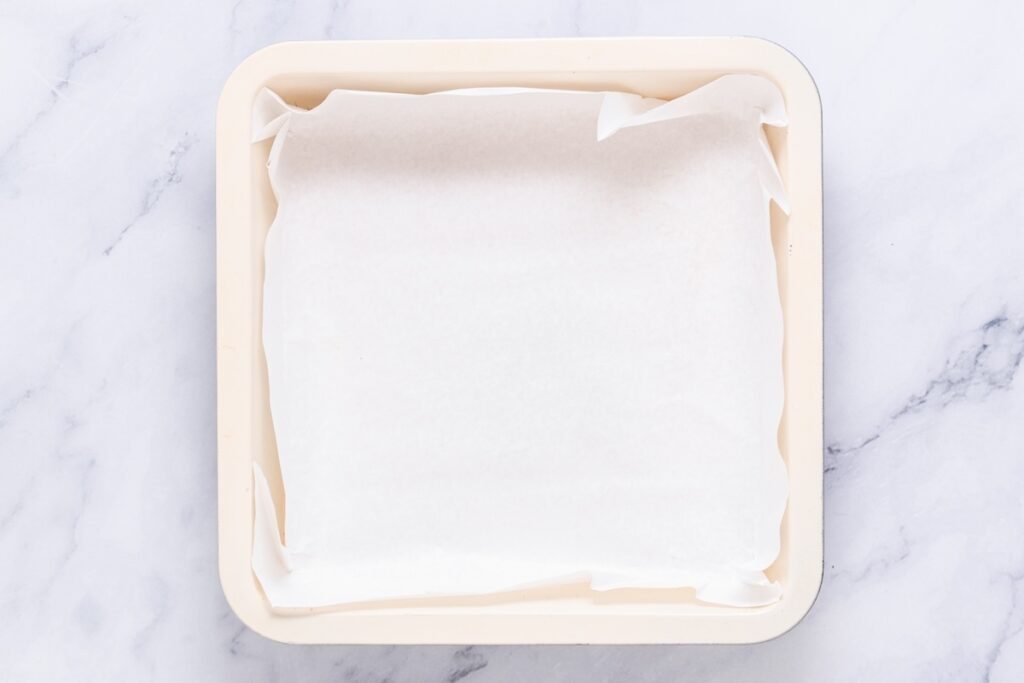 A baking tray perfectly lined with parchment paper rests elegantly on the marble surface.