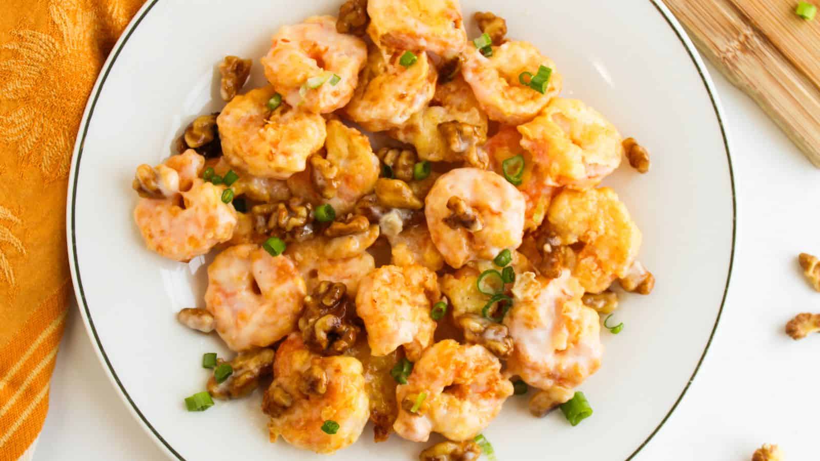 A plate of honey walnut shrimp topped with green onions.