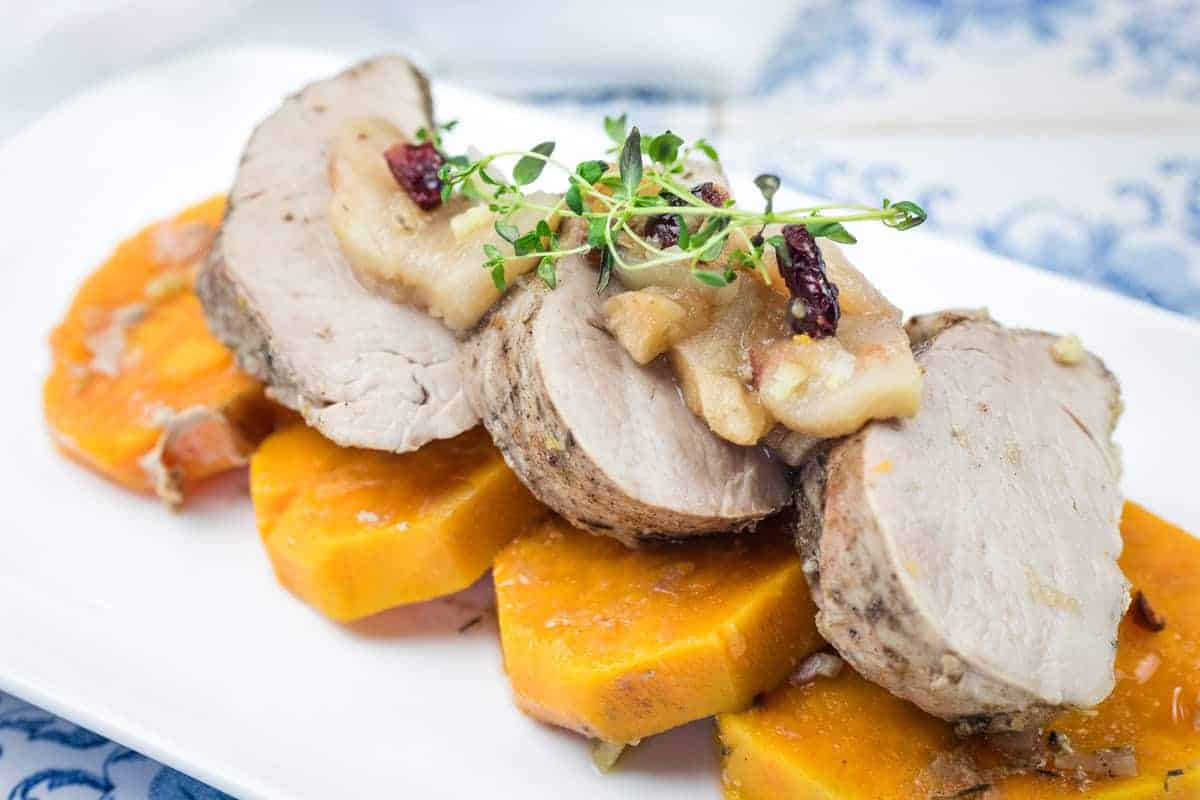A serving of Slow Cooker Pork Tenderloin with Sweet Potatoes & Apples on a white platter.