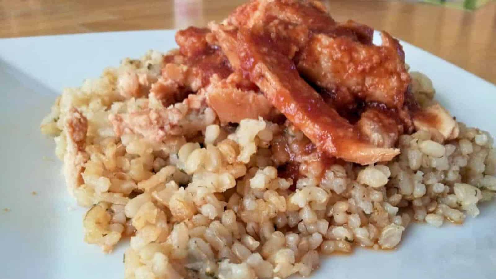 Plate of rice topped with shredded chicken in red sauce.