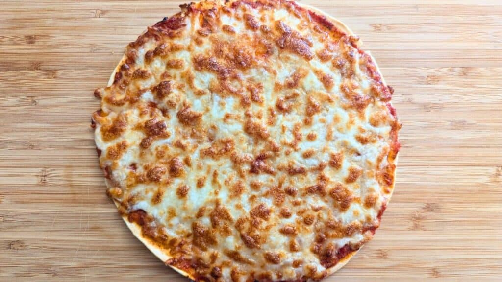 A freshly baked cheese pizza on a wooden board.