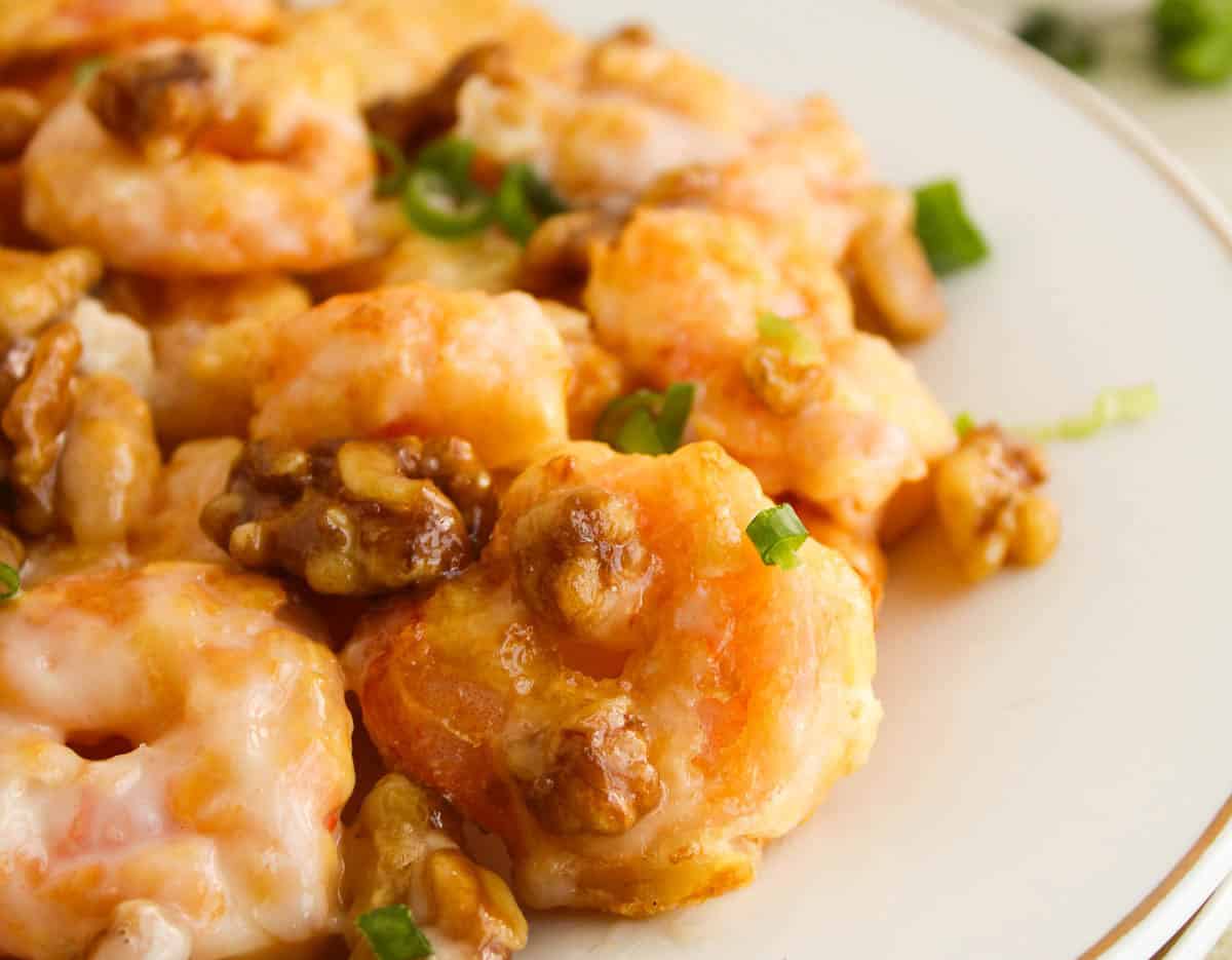 Close-up of plated honey walnut shrimp with a bowl of walnuts.