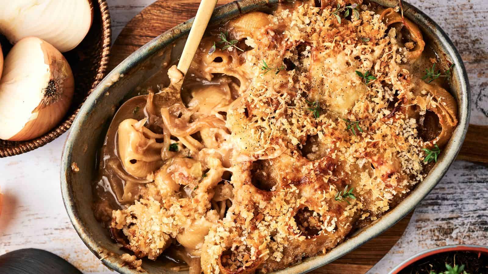 A baked casserole dish filled with creamy macaroni and cheese, topped with a golden-brown breadcrumb crust and garnished with fresh herbs.