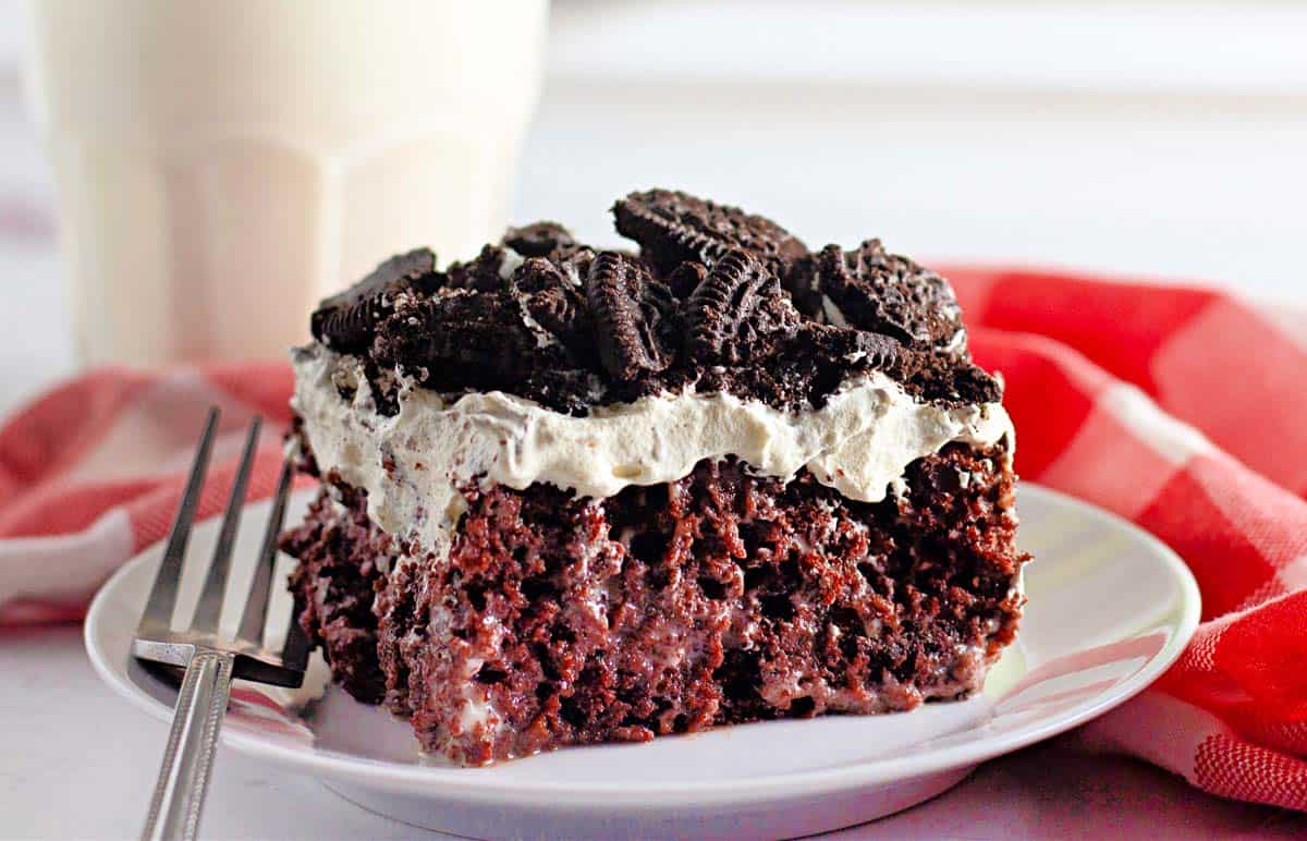 A slice of Oreo poke cake on a white plate.