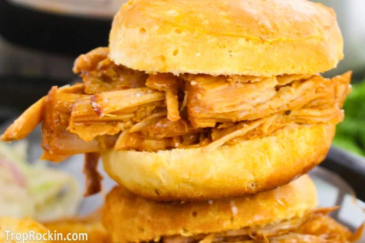 A pulled shredded chicken sandwich in barbecue sauce on a golden bun, shown close-up.