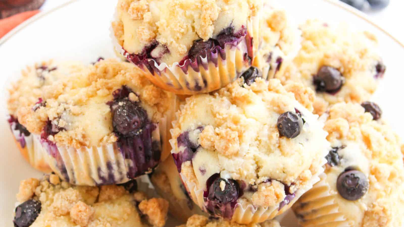A plate of blueberry muffins with crumb topping, arranged in a pile.