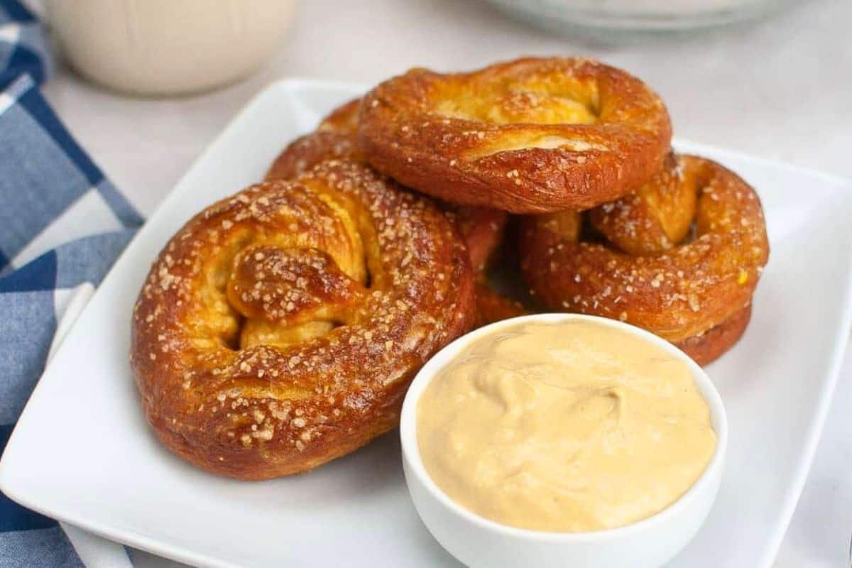 Five sourdough soft pretzels stacked on a plate.